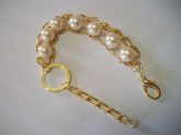 Pulseira de pérolas e corrente dourada.